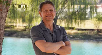 TCC Professor Neil Enis stands arms folding in front the pond at TCC Southeast Campus.