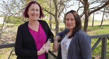 TCC psychology professors Dr. Jen Ivie and Dr. Alicia MacKay pose together outside.