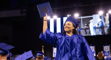 A student holds up her degree at the Spring 2024 Commencement ceremony.