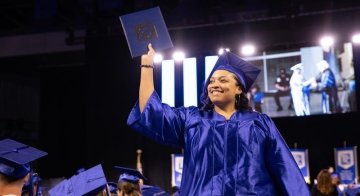 A student holds up her degree at the Spring 2024 Commencement ceremony.