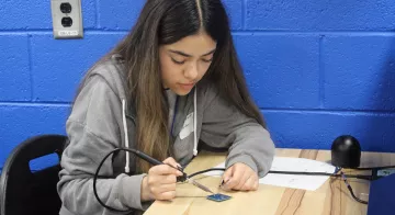 A student solders a circuit board