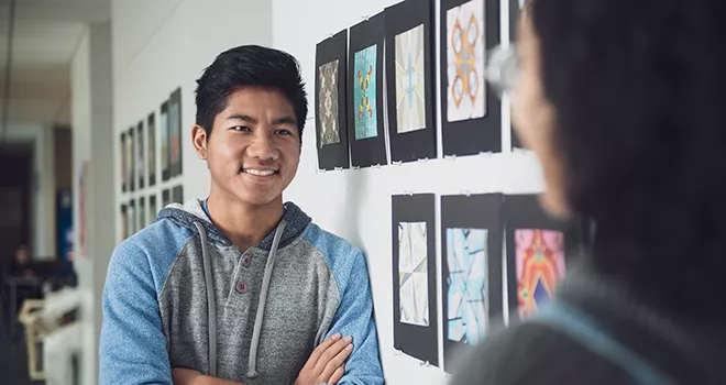 TCC art student stands in front of a wall of artistic prints.