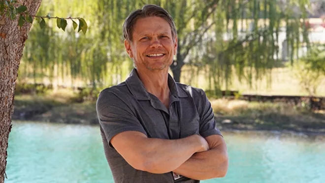 TCC Professor Neil Enis stands arms folding in front the pond at TCC Southeast Campus.