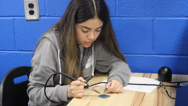 A student solders a circuit board