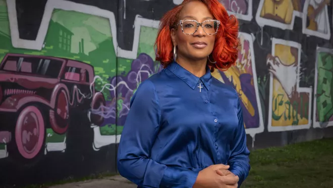 TCC Professor, Corinice Wilson, Ph.D. stands in front of the mural at Black Wall St..