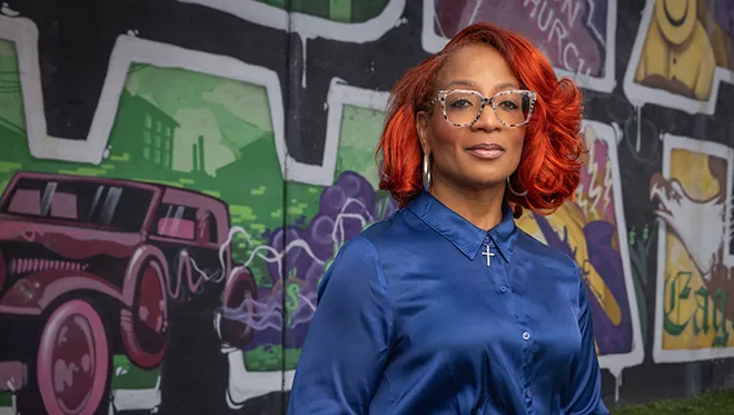 TCC Professor, Corinice Wilson, Ph.D. stands in front of the mural at Black Wall St..