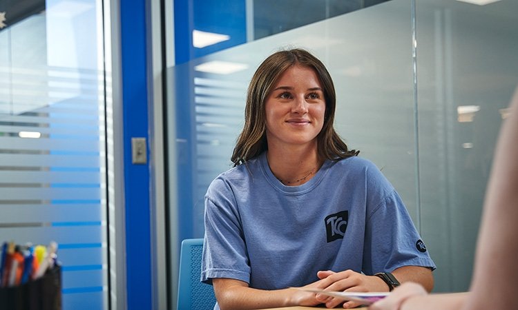 Young woman wearing blue tcc shirt gets help from a staff member