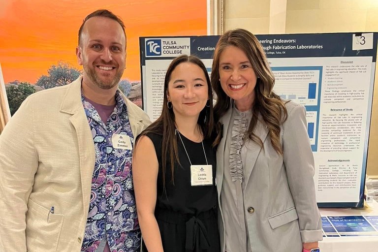 Cody Zimmer, Leahla Chism and Dr. Sheila Youngblood smile next to Chism's research presentation.