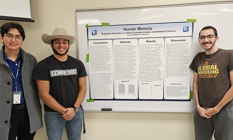 TCC psychology students stand next to their research presentation board.